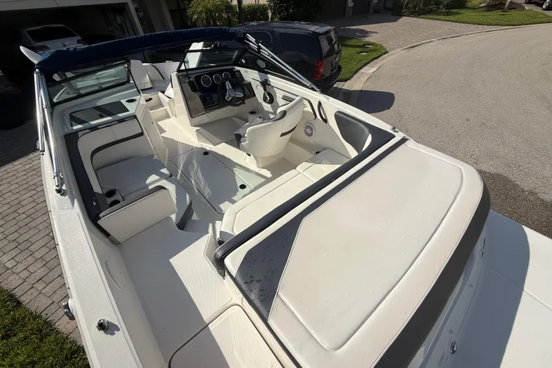 Slide: The Image of 2018 Sea Ray SPX 190 boat interior with seating and steering wheel, parked on a driveway. - 19