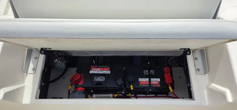 Slide: The Image of 2023 Cobia 220 Center Console boat battery compartment with dual batteries and wiring. - 14