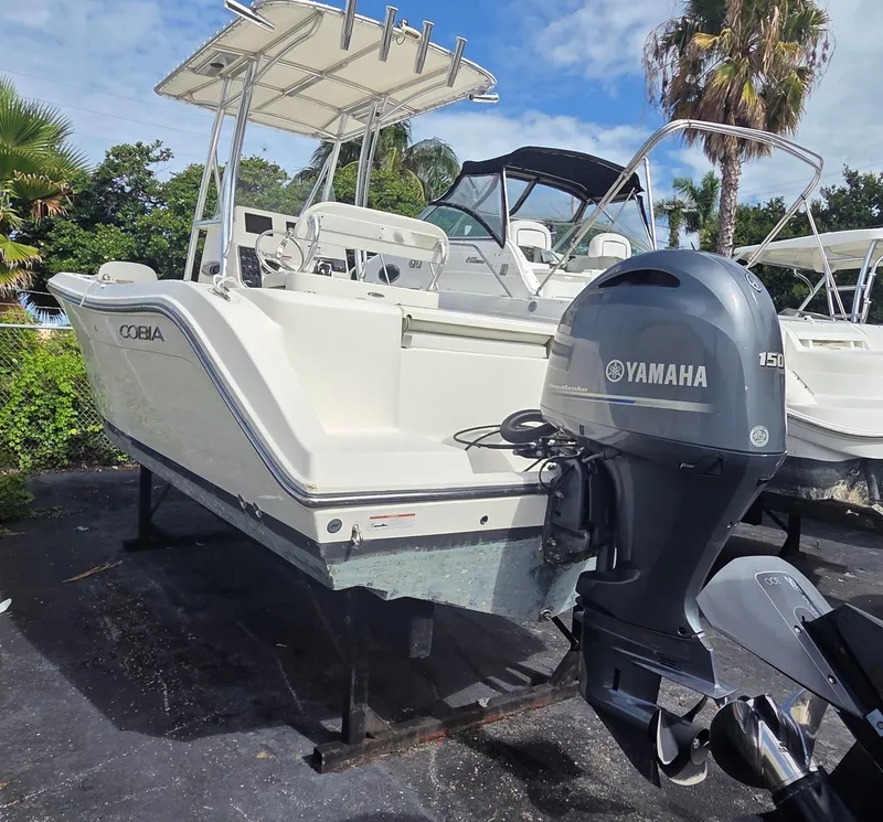 Slide: The Image of 2023 Cobia 220 Center Console boat with Yamaha 150 outboard motor, parked outdoors. - 2