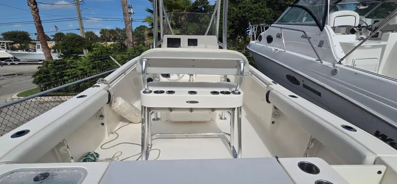 Slide: The Image of 2023 Cobia 220 Center Console boat with spacious deck and seating, docked outdoors. - 3