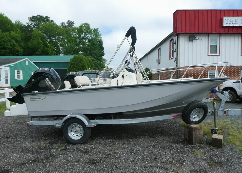 Slide: The Image of 2025 Boston Whaler 170 Montauk boat on trailer, parked outdoors near buildings. - 0