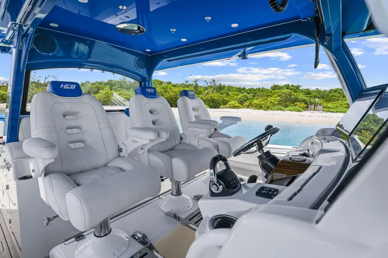 Slide: The Image of Luxurious 2020 HCB 53 boat interior with plush seating and advanced controls, near a scenic beach. - 16