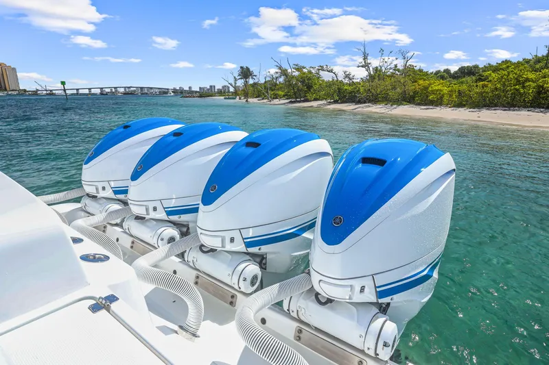 Slide: The Image of Four blue and white outboard motors on a 2020 HCB 53 boat near a tropical shoreline. - 19