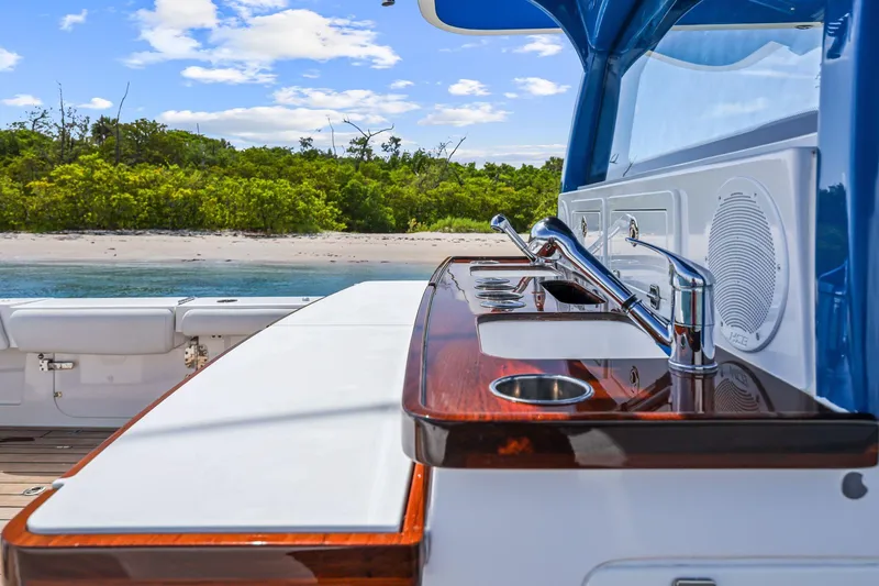 Slide: The Image of Luxury HCB 53 yacht kitchen area with sink, overlooking serene beach and lush greenery. - 38