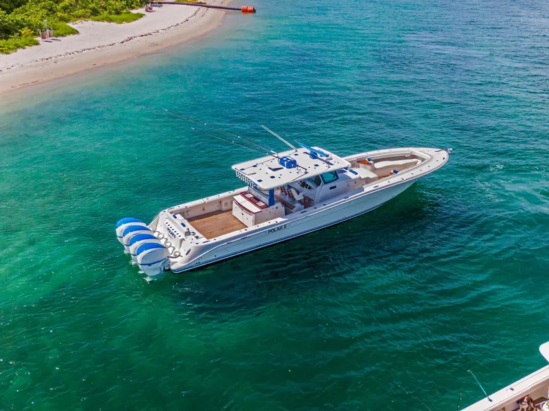 Slide: The Image of Aerial view of 2020 HCB 53 boat cruising in clear turquoise waters near a sandy beach. - 47