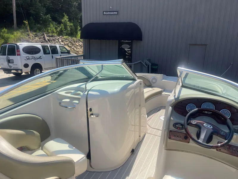 Slide: The Image of 2005 Sea Ray 220 Sundeck interior with steering wheel and seating, parked near a building. - 4
