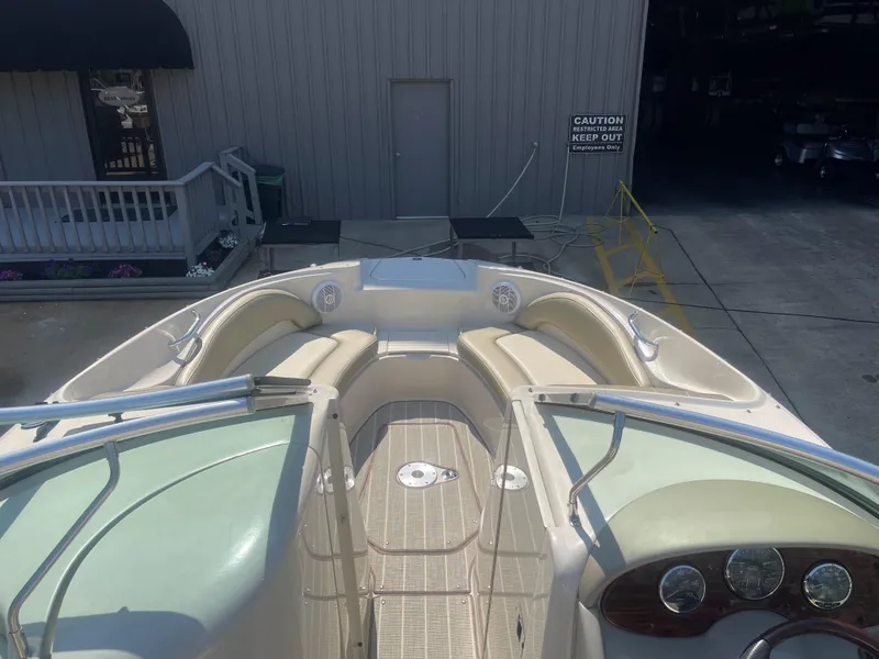 Slide: The Image of 2005 Sea Ray 220 Sundeck boat interior with seating and dashboard, docked near a building. - 5
