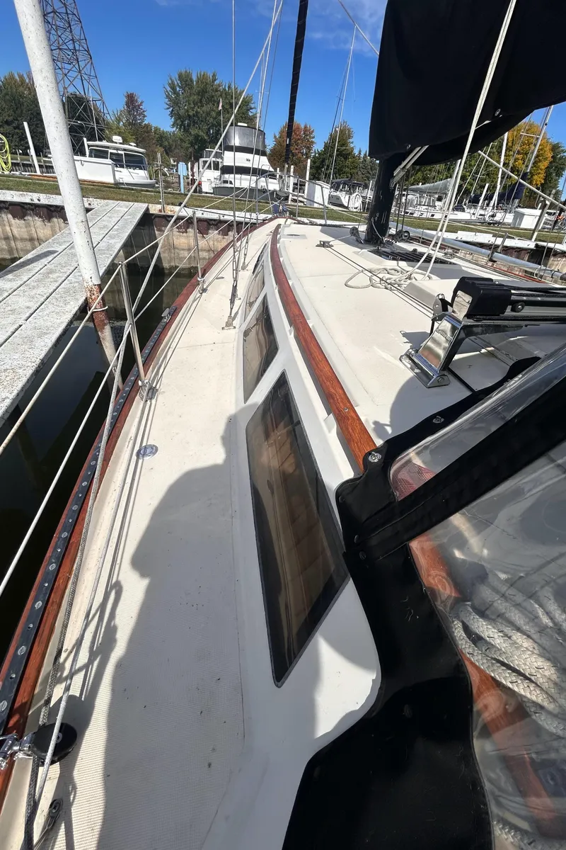 Slide: The Image of 1982 S2 11.0 A sailboat docked, showcasing deck and cabin windows. - 10