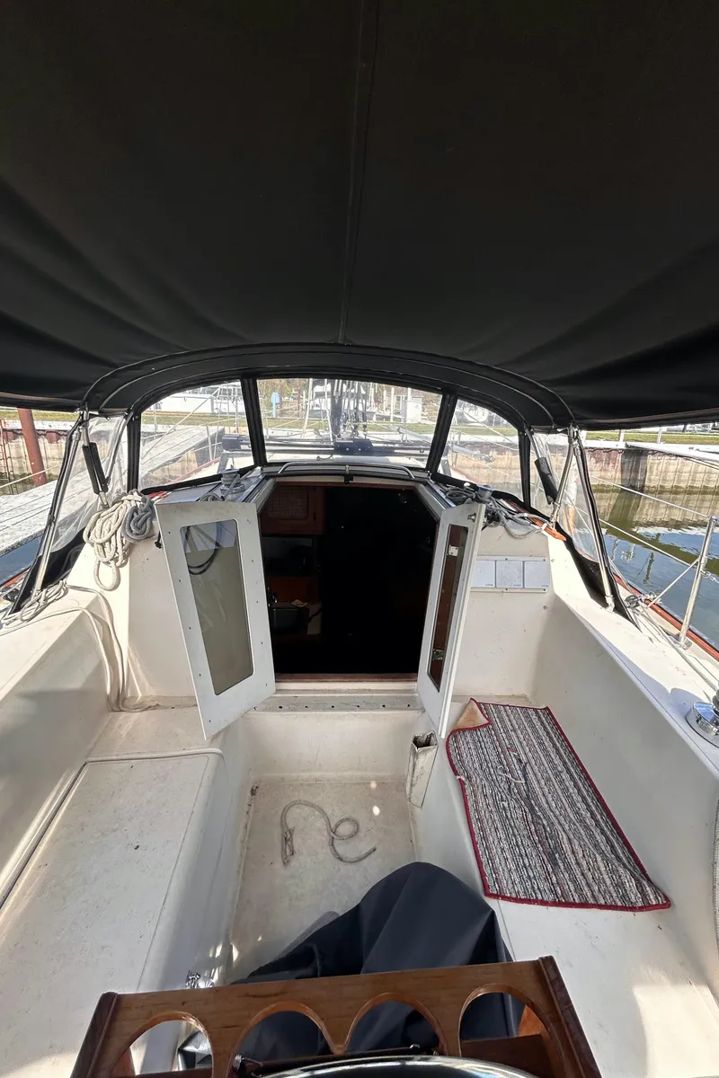 Slide: The Image of 1982 S2 11.0 A sailboat cockpit with open cabin doors and canopy. - 11