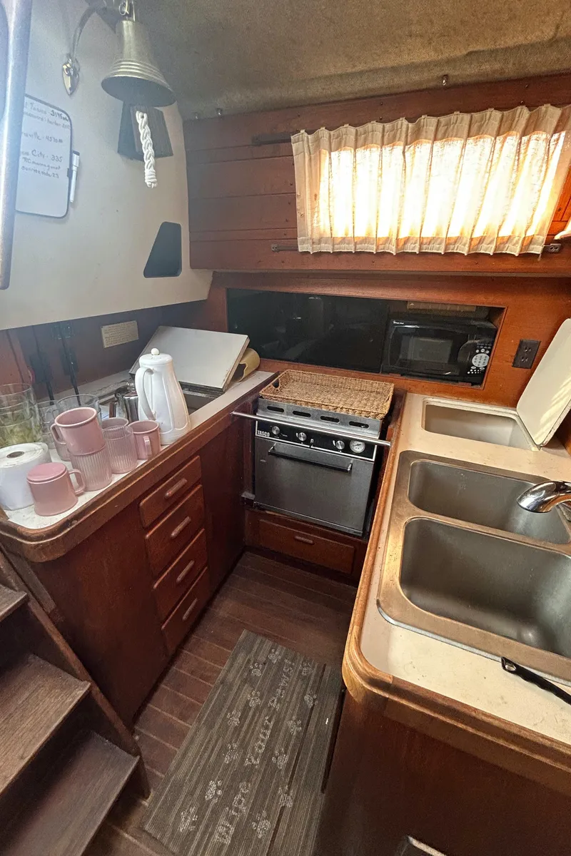 Slide: The Image of 1982 S2 11.0 A yacht kitchen with wooden cabinets, stove, and dual sinks. - 15