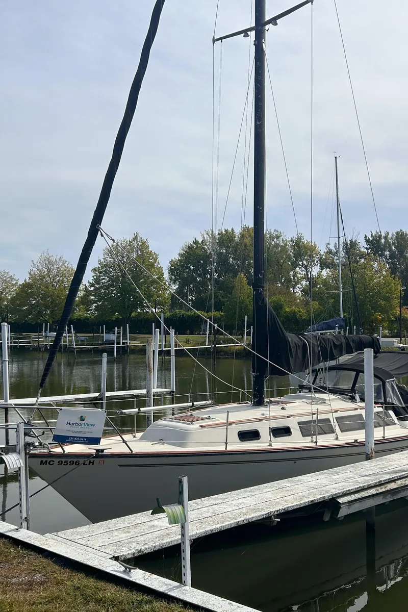 Slide: The Image of 1982 S2 11.0 A sailboat docked at a marina with trees in the background. - 2