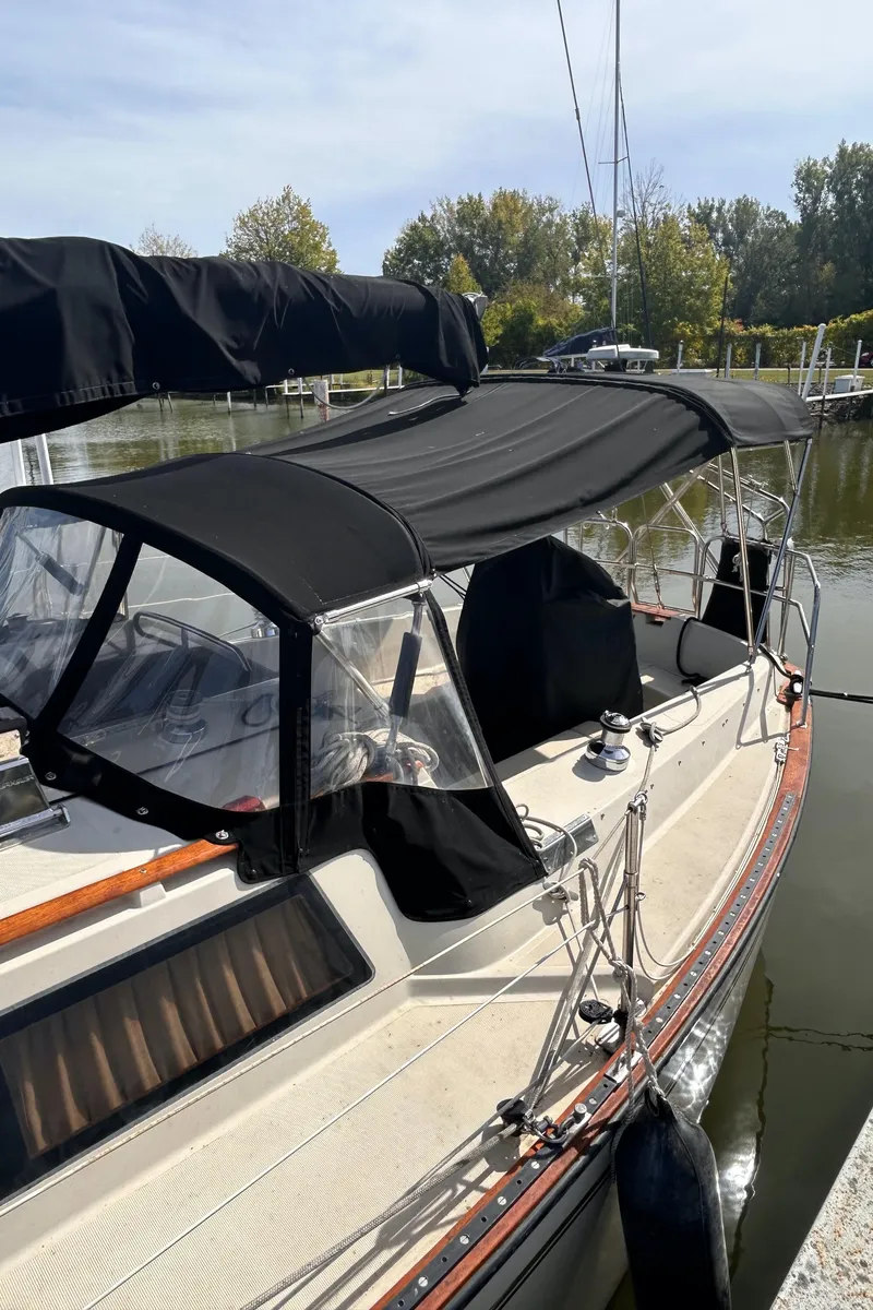 Slide: The Image of 1982 S2 11.0 A sailboat with black canopy docked in a marina. - 3