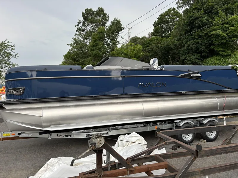 The Image of 2025 Avalon Catalina Quad Lounger Windshield pontoon boat on trailer, parked outdoors. - 0
