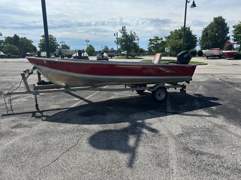 Slide: The Image of 2021 Lund SSV-16 boat on trailer in parking lot, red and silver design. - 5