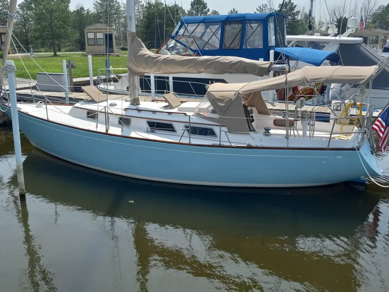 The Image of 1980 Bristol 35.5 sailboat docked in marina, featuring light blue hull and beige covers. - 0