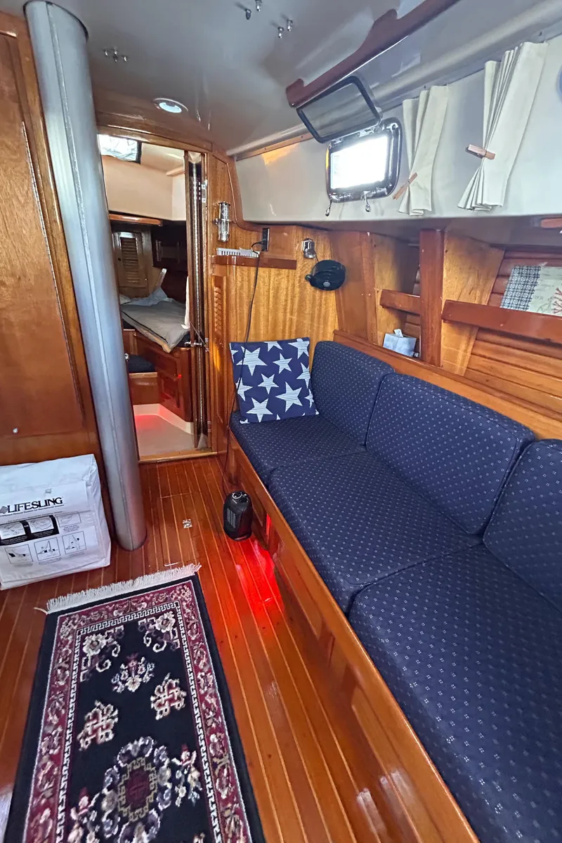 Slide: The Image of 1980 Bristol 35.5 yacht interior with blue seating, wooden flooring, and nautical decor. - 10
