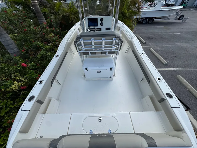 Slide: The Image of 2025 Key West 239 FS boat interior with console and seating, parked near tropical foliage. - 10