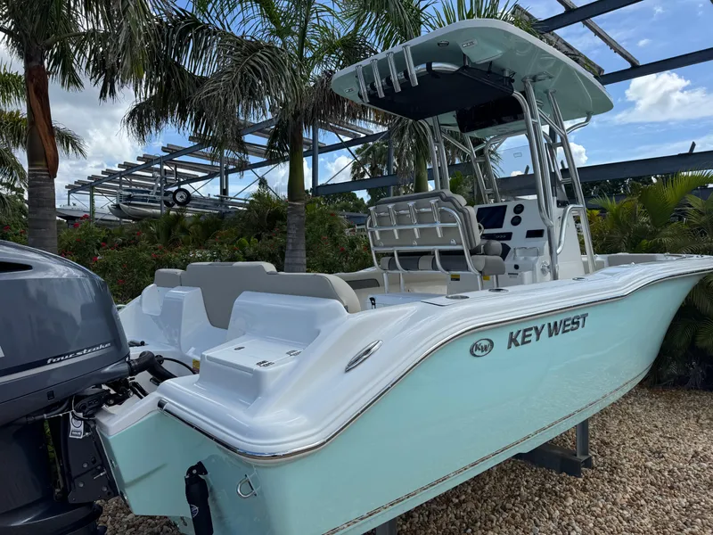 Slide: The Image of 2025 Key West 239 FS boat with outboard motor, parked among palm trees. - 5
