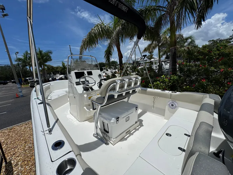 Slide: The Image of 2025 Key West 203 FS boat interior with seating, steering console, and palm trees in the background. - 12