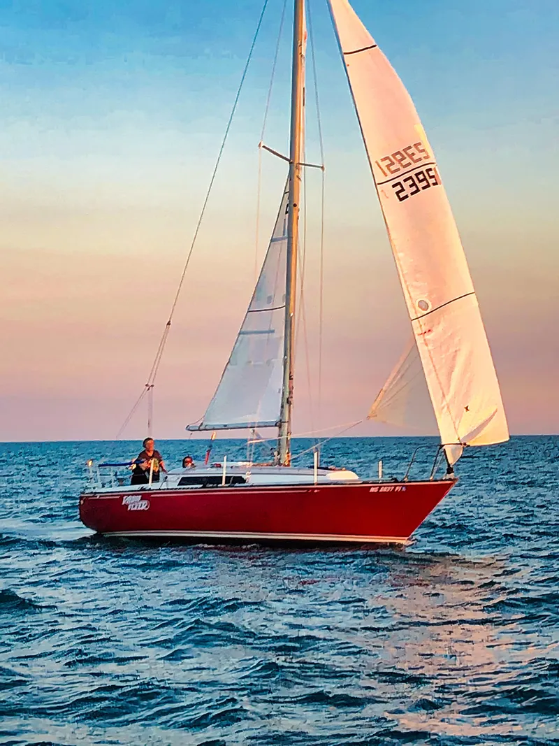 Slide: The Image of Red 1979 C&C 29 sailboat gliding on calm ocean waters at sunset. - 1