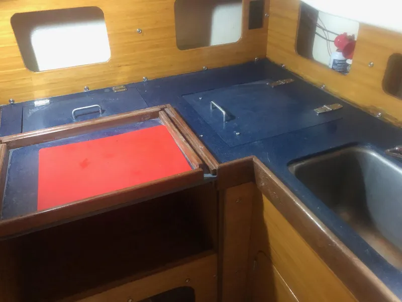 Slide: The Image of 1979 C&C 29 sailboat galley with wooden cabinetry, blue countertops, and stainless steel sink. - 6