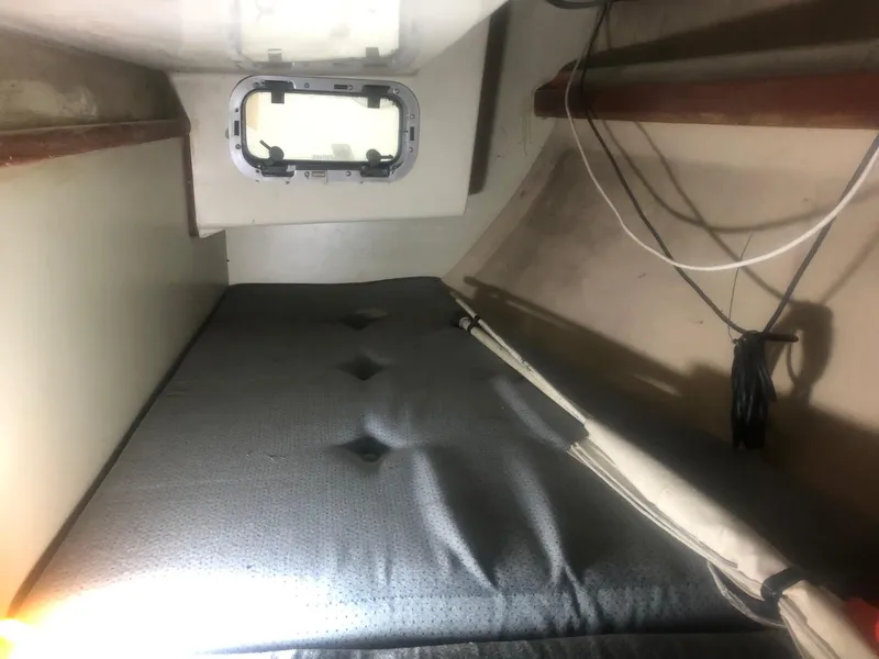 Slide: The Image of 1979 C&C 29 sailboat interior cabin with a cushioned berth and porthole. - 9