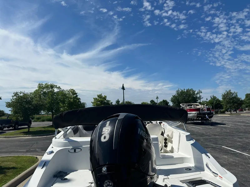 Slide: The Image of 2016 Tahoe 2150 boat with Mercury engine in a parking lot under a blue sky. - 2