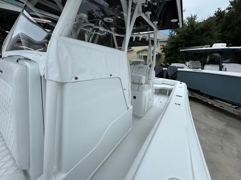 Slide: The Image of 2021 Yellowfin 36 Offshore boat interior with white seating and console, parked outdoors. - 24
