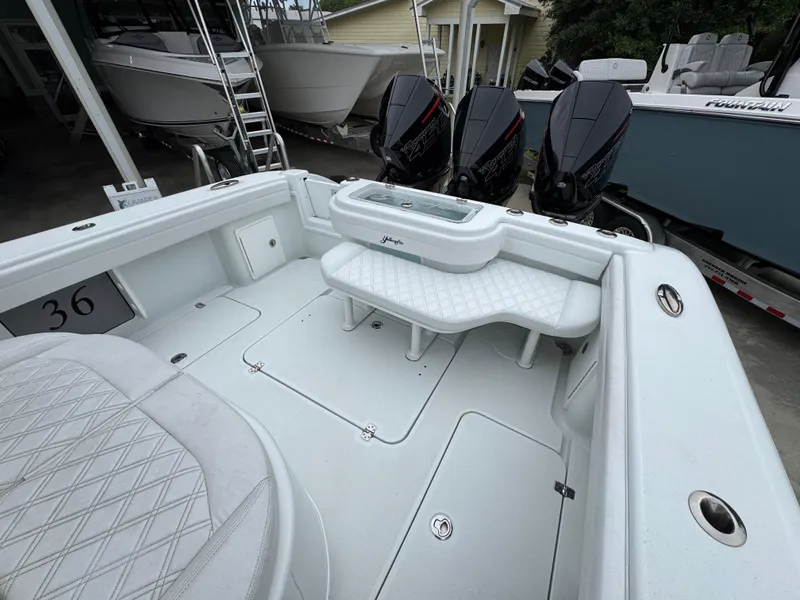 Slide: The Image of 2021 Yellowfin 36 Offshore boat interior with triple outboard engines, white seating, and storage compartments. - 35