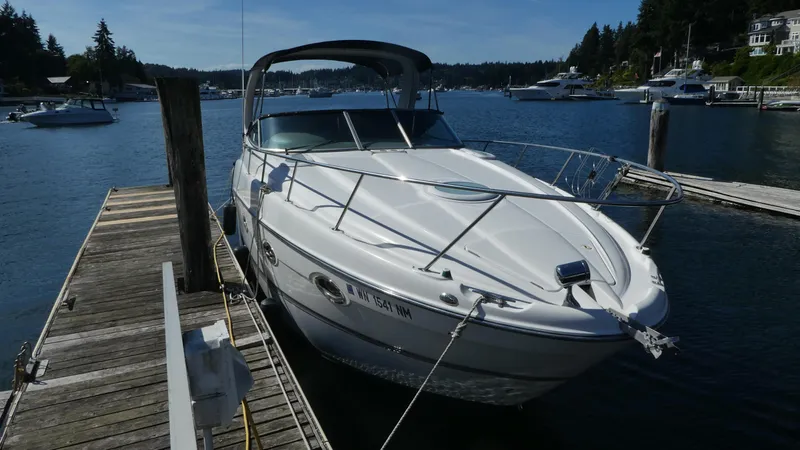 The Image of 2002 Maxum 3100 SCR boat docked at a marina, surrounded by calm water and other boats. - 0