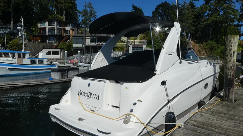 Slide: The Image of 2002 Maxum 3100 SCR boat docked at marina, surrounded by waterfront homes and trees. - 2