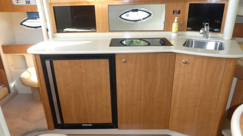 Slide: The Image of 2002 Maxum 3100 SCR boat interior kitchen with sink, stove, and wooden cabinetry. - 22