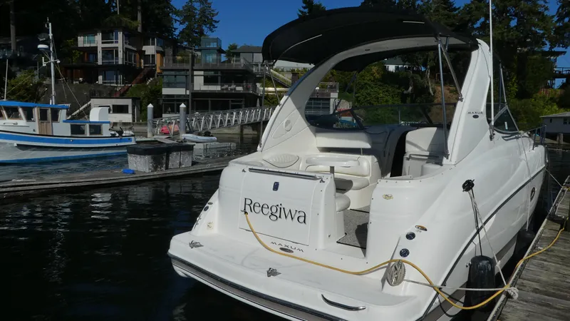 Slide: The Image of 2002 Maxum 3100 SCR boat docked at a marina with waterfront homes. - 3