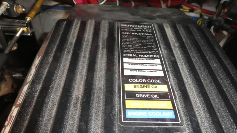 Slide: The Image of MerCruiser engine cover with specifications and color-coded fluid labels on a 2002 Maxum 3100 SCR. - 33