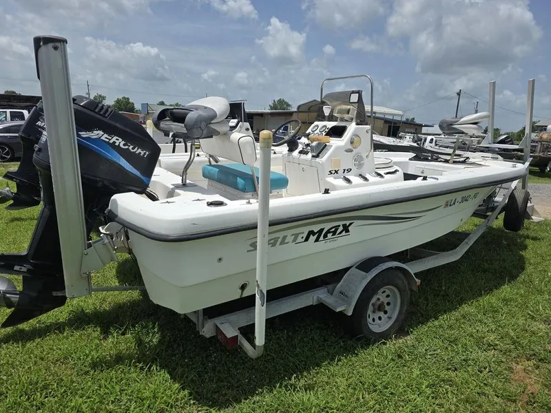 Slide: The Image of 2002 Sprint Salt-Max boat on trailer with Mercury engine, parked on grass under cloudy sky. - 2