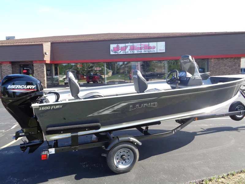 The Image of 2025 Lund 1600 Fury SS boat on trailer, parked outside a marine store. - 0