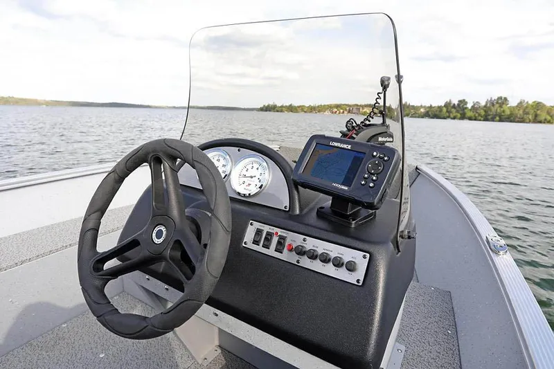 Slide: The Image of Manufacturer Provided Image: 2025 Lund 1600 Fury SS boat dashboard with steering wheel and navigation system on a lake. - 14
