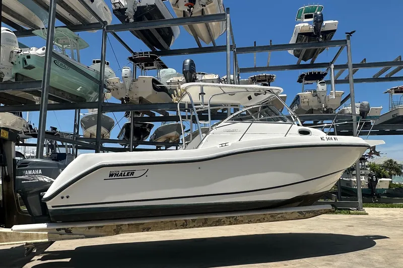 The Image of 2002 Boston Whaler 255 Conquest boat on dry dock, surrounded by other vessels. - 1