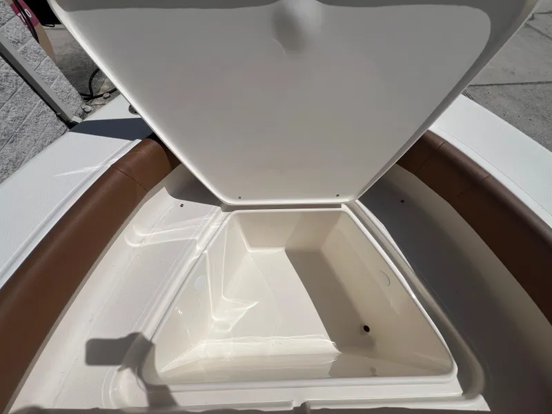 Slide: The Image of Open storage compartment on 2026 Pioneer 180 Islander boat, featuring brown seating and white interior. - 19