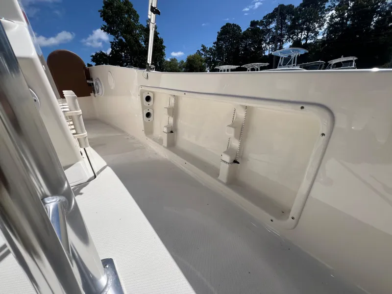 Slide: The Image of 2026 Pioneer 180 Islander boat interior with storage compartment and seating, under clear blue sky. - 24