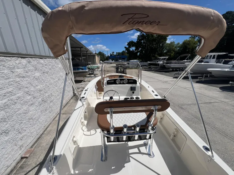 Slide: The Image of 2026 Pioneer 180 Islander boat with canopy, docked outdoors under blue sky. - 8