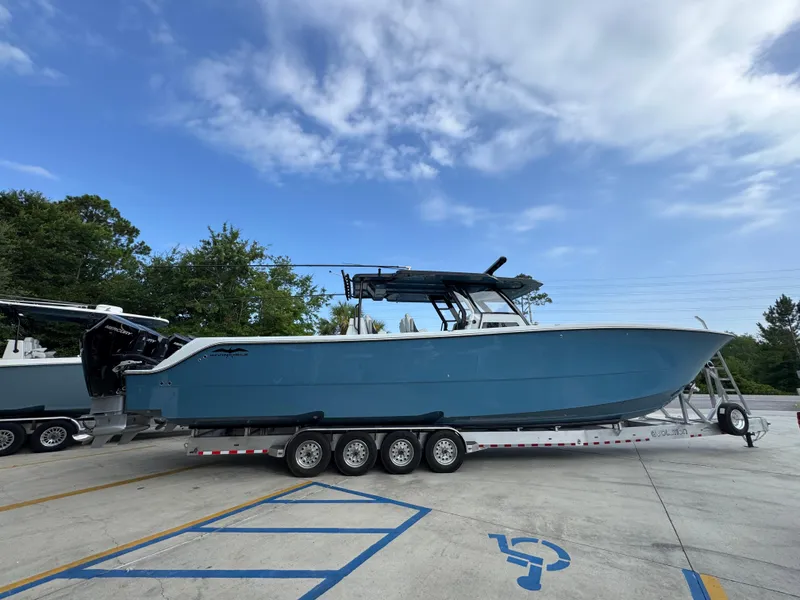Slide: The Image of 2026 Invincible 46 Catamaran on trailer, blue hull, parked outdoors under cloudy sky. - 10