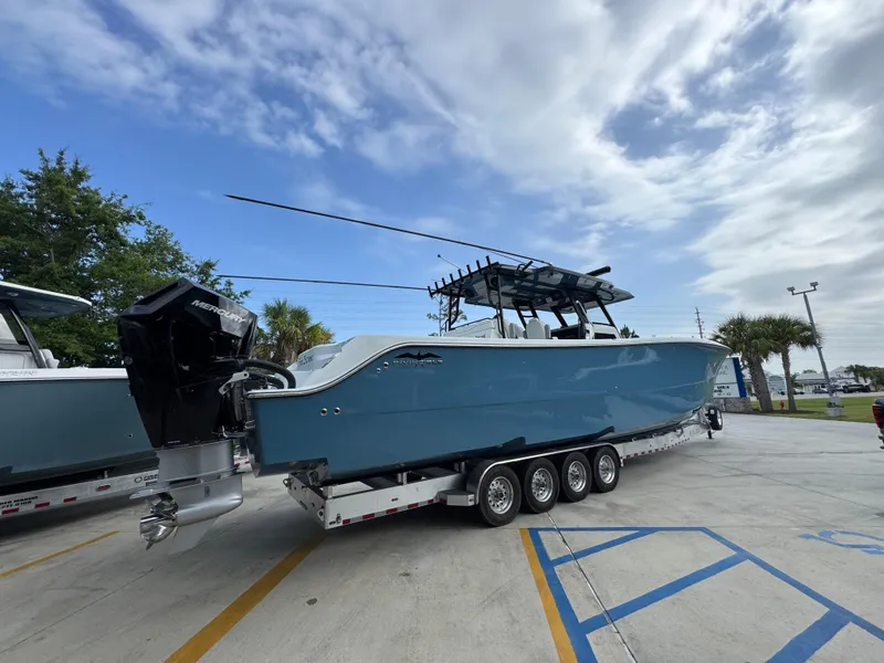 Slide: The Image of 2026 Invincible 46 Catamaran on trailer, blue hull, parked outdoors under cloudy sky. - 11