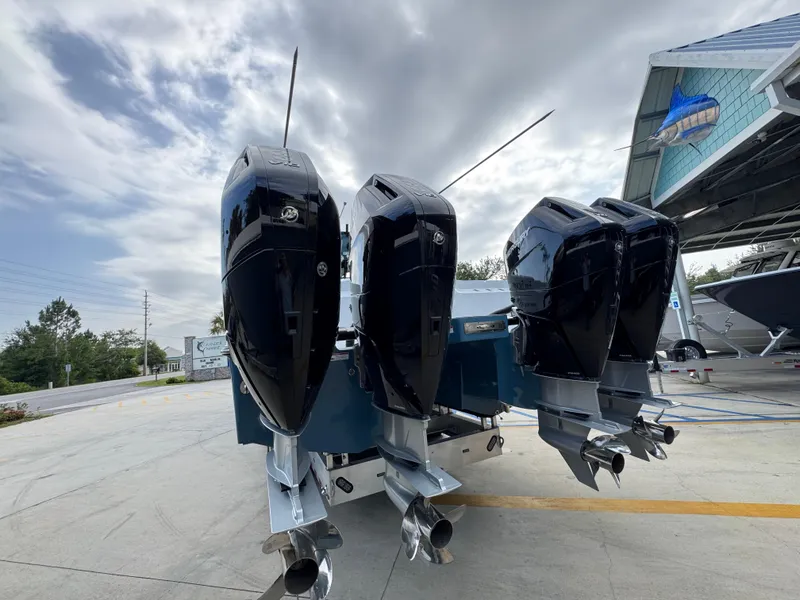 Slide: The Image of Four powerful outboard motors on a 2026 Invincible 46 Catamaran under a cloudy sky. - 15
