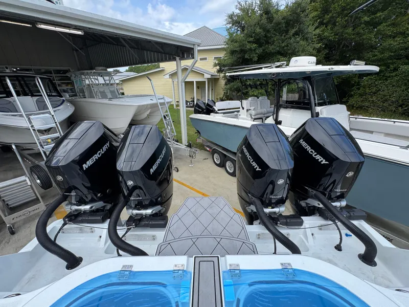 Slide: The Image of Four Mercury outboard engines on a 2026 Invincible 46 Catamaran, docked near other boats. - 39