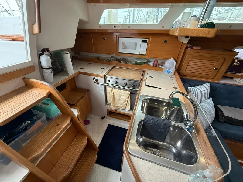Slide: The Image of Interior of 2000 Catalina 36 MkII sailboat kitchen with sink, stove, and wooden cabinetry. - 32