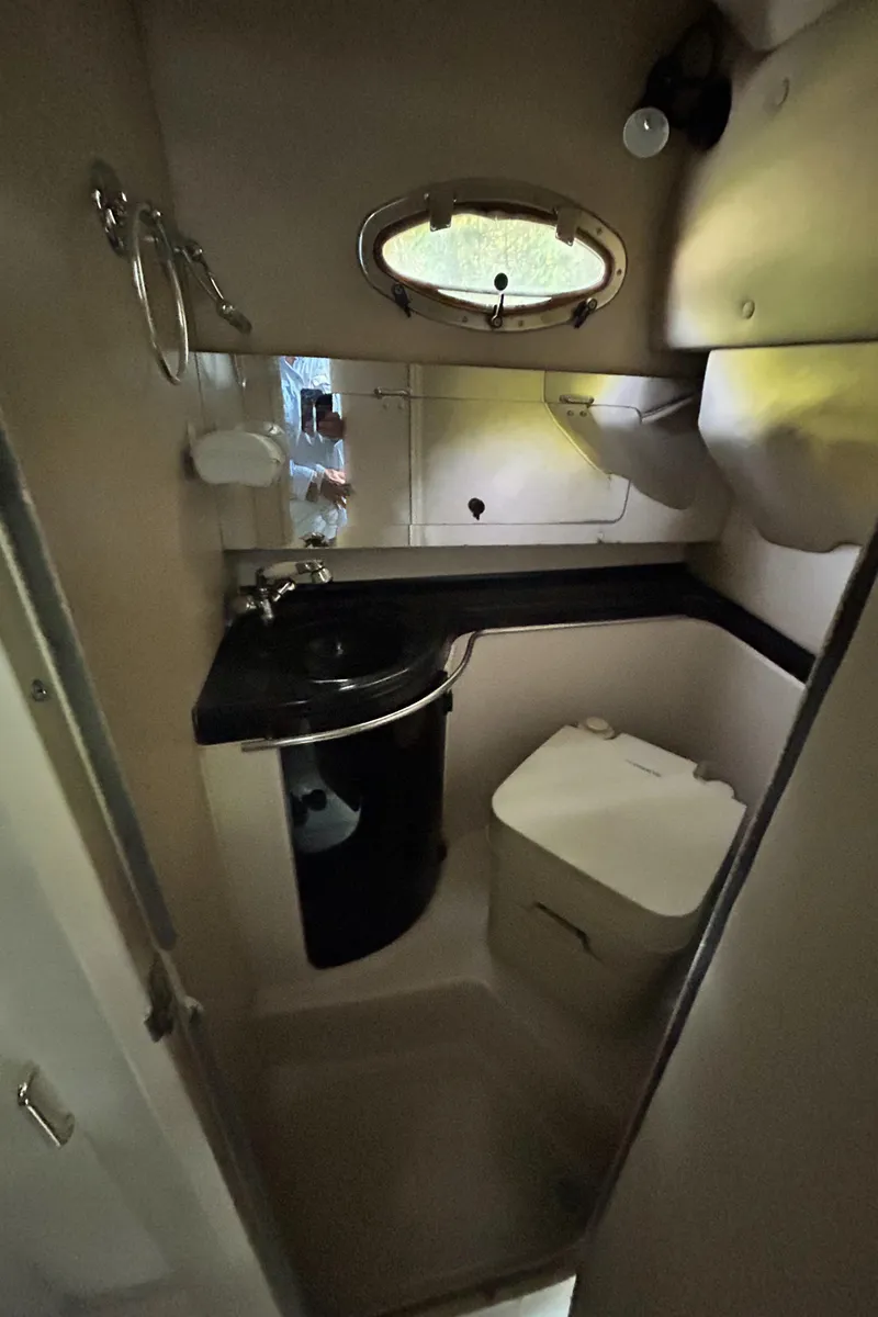 Slide: The Image of 1995 Donzi 255 Medallion boat bathroom with sink, toilet, and porthole window. - 9
