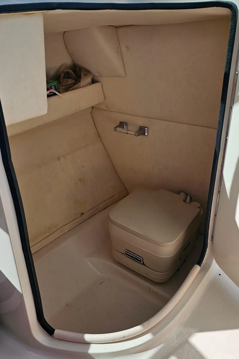 Slide: The Image of 2005 Sea Ray 220 Sundeck interior with portable toilet and storage shelf. - 13