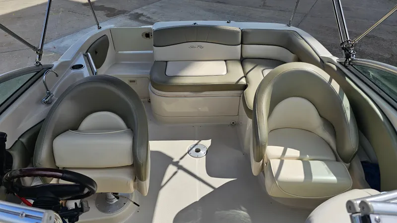 Slide: The Image of 2005 Sea Ray 220 Sundeck interior with beige seating and steering wheel. - 18