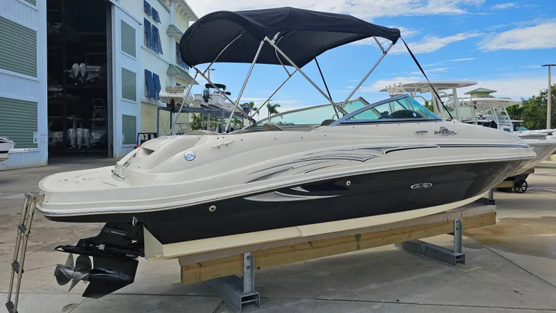 Slide: The Image of 2005 Sea Ray 220 Sundeck boat with canopy, displayed on a stand in a marina. - 4